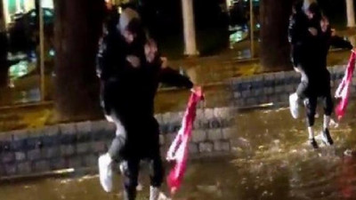 İki genç yağmur sularına düşen Türk bayrağını yerden kaldırdı